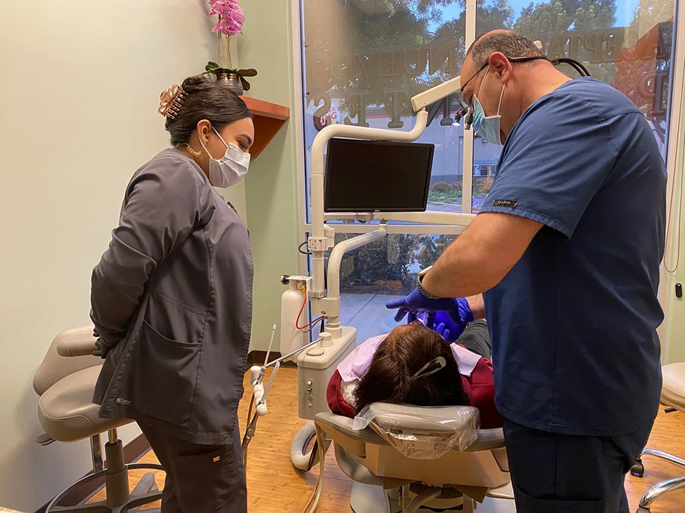 Dentist and dental assistant providing care to a patient at Brilla Dental Group practice in Santa Maria, CA.